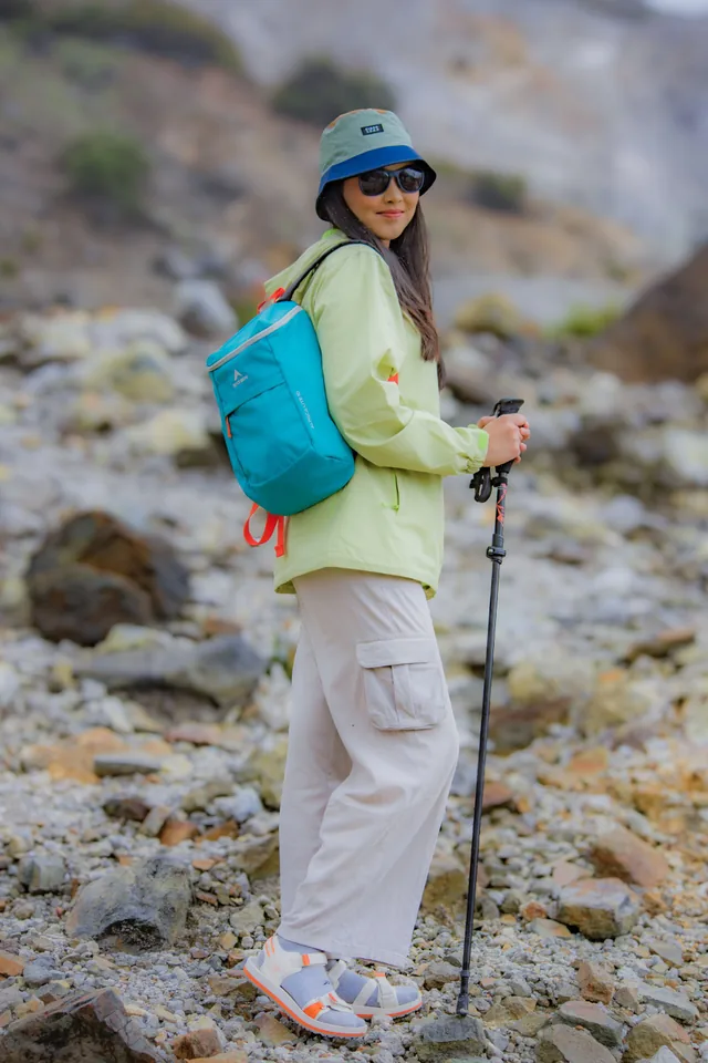Hiker with a backpack and trekking pole on rocky terrain